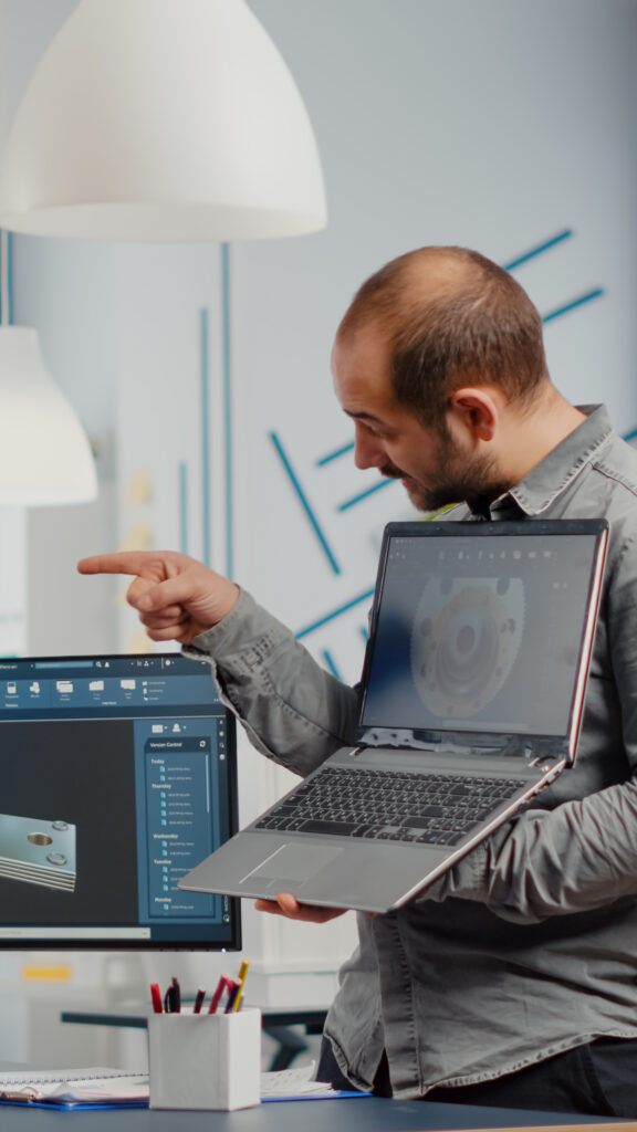 Man project supervisor holding laptop and pointing on display